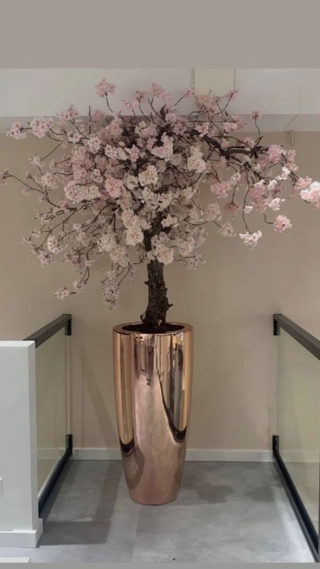 a vase filled with pink flowers sitting on top of a gray floor next to a wall