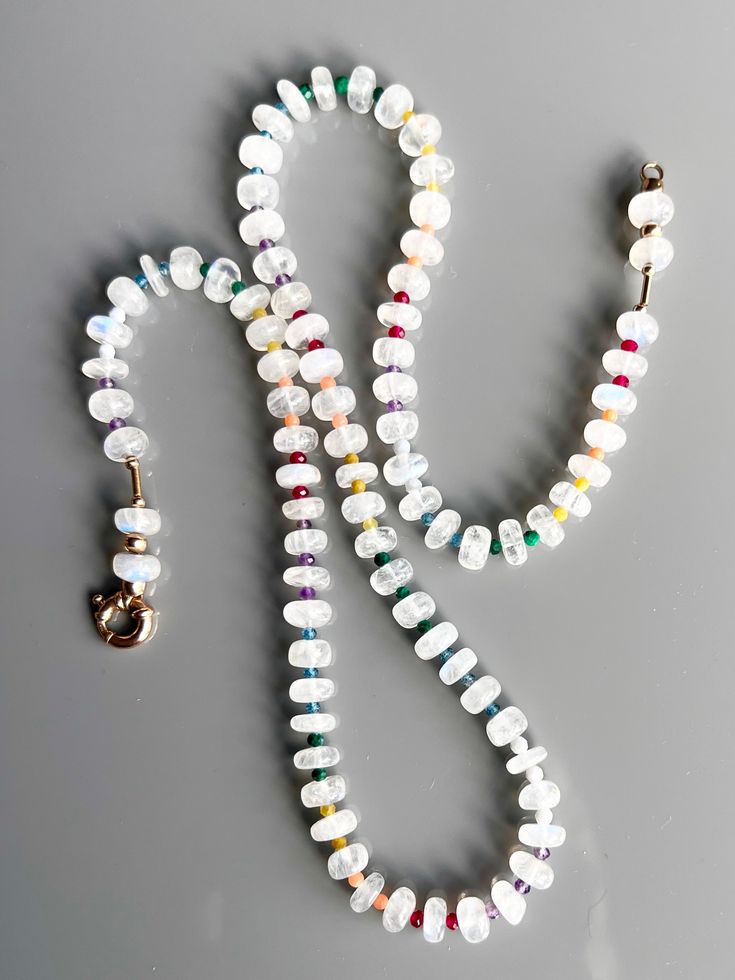 a white beaded necklace with a gold charm on the end and an earring attached to it