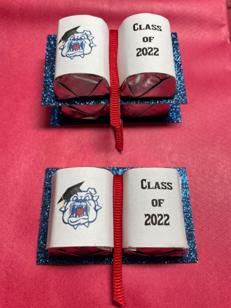 two books with graduation caps on them are sitting on a red tablecloth covered table