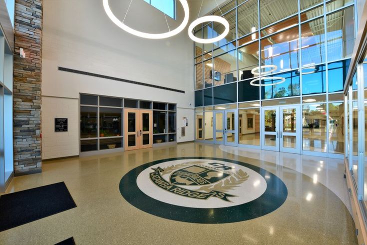 the inside of a large building with glass doors and a circular logo on the floor