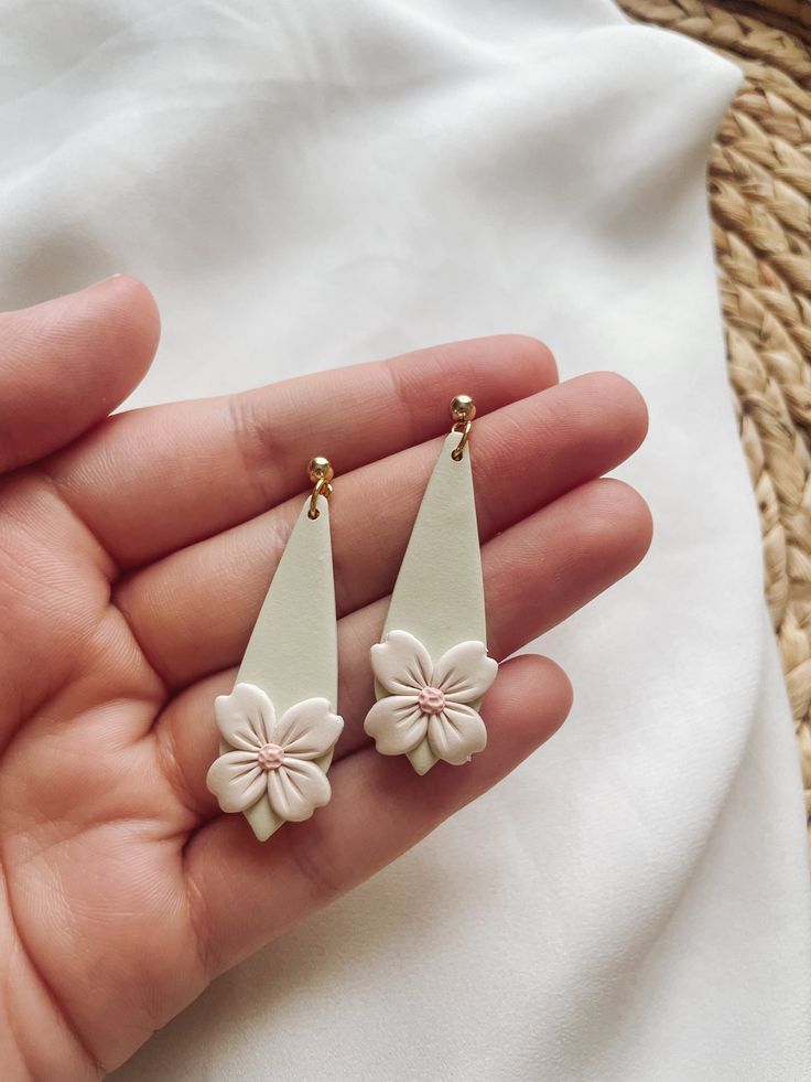 a pair of white flower earrings on a person's hand