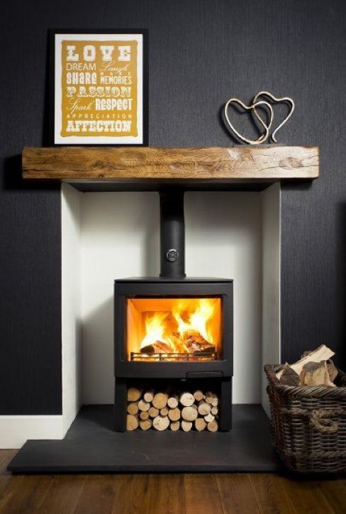 a wood burning stove in a room with black walls and wooden flooring on the side