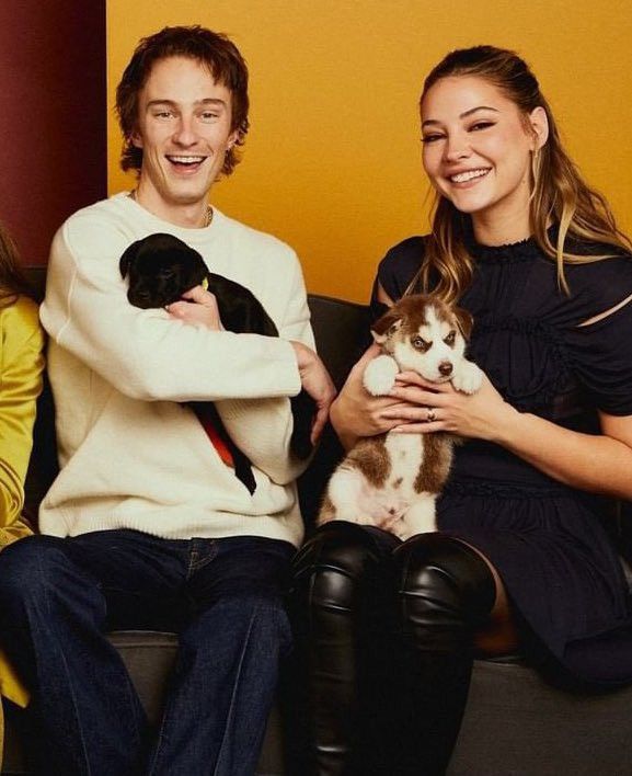 three people sitting on a couch holding cats