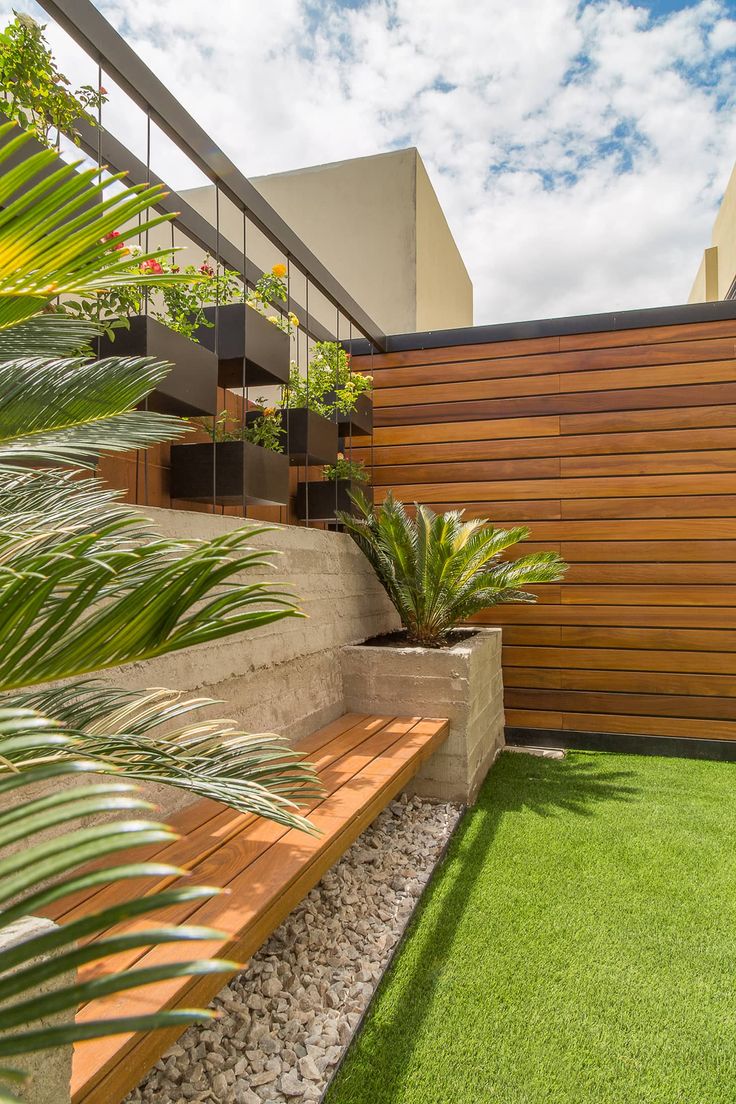 a wooden bench sitting on top of a lush green field next to a tall building