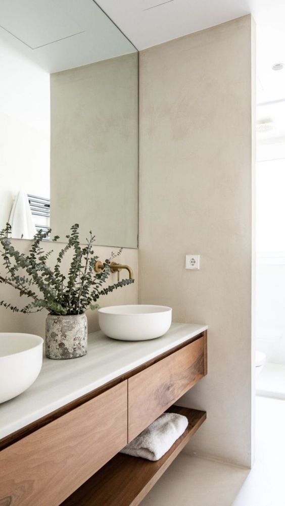 two white bowls are sitting on the counter in front of a large mirror and sink