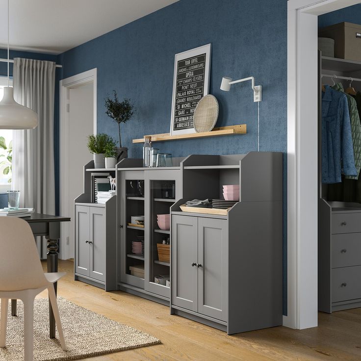 a room with a chair, desk and cabinets in the corner that are both grey