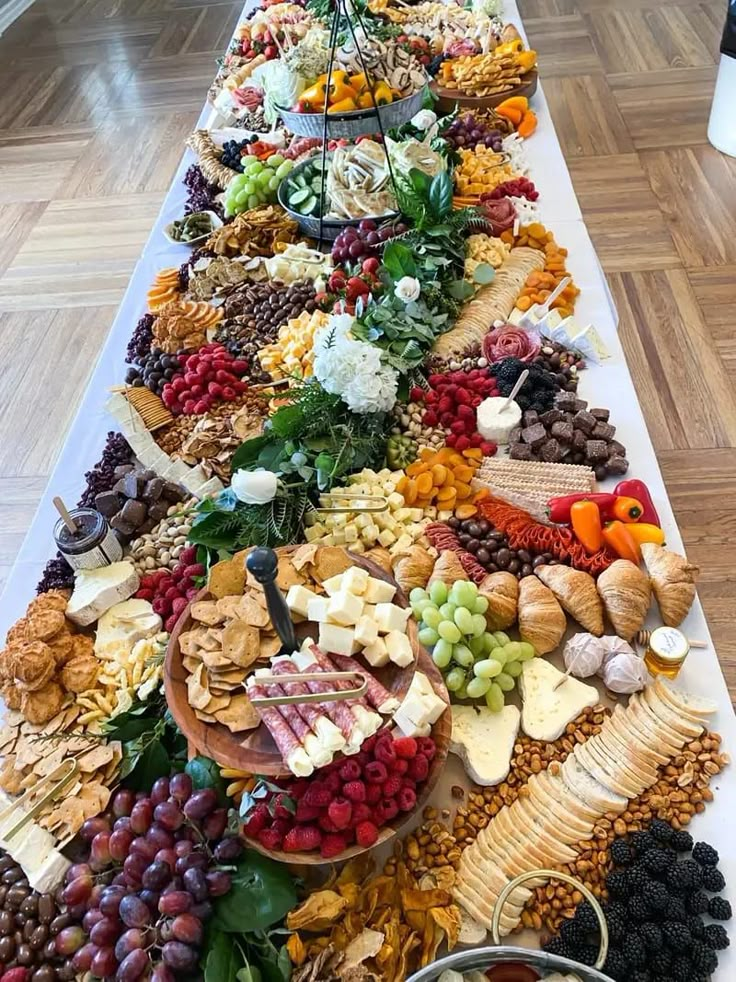 a long table filled with lots of different types of food on top of wooden floors