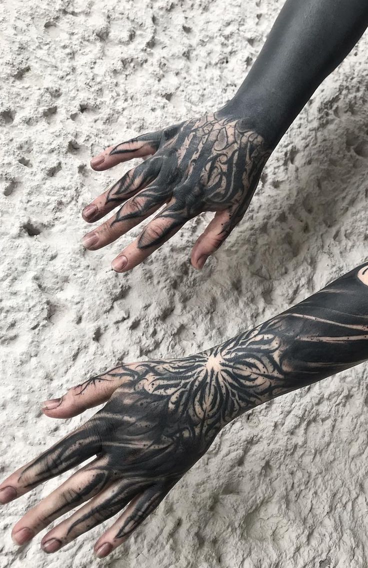 two hands with black and white tattoos on them