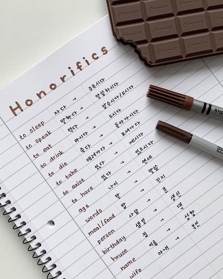 two pens sitting on top of a notebook next to chocolate