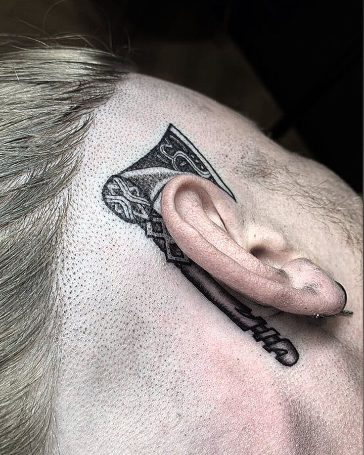 a man with a tattoo on his head has an ear piece in the shape of a hammer