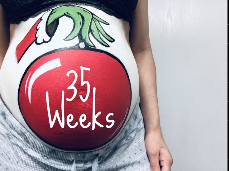 a pregnant woman holding her belly painted with the words 35 weeks