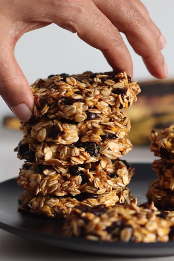 a hand reaching for granola cookies on a plate