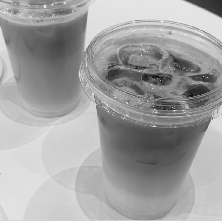 two drinks sitting next to each other on top of a white table covered in ice