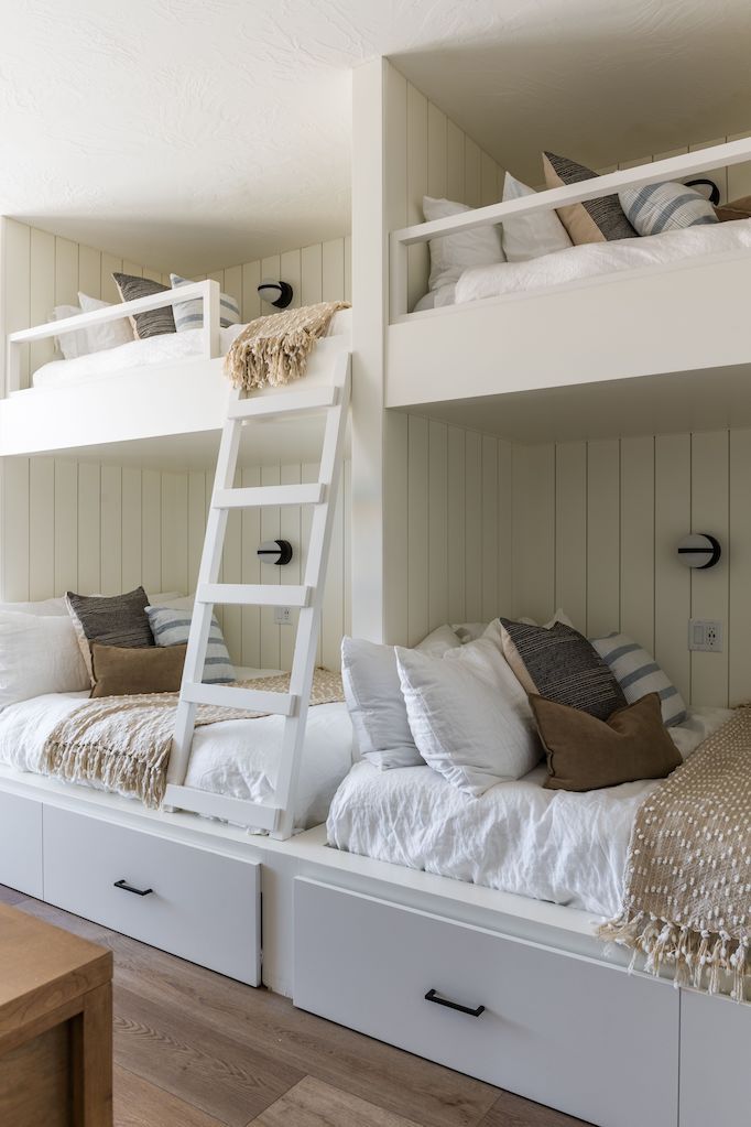 bunk beds with drawers underneath them in a room that has white walls and wood floors