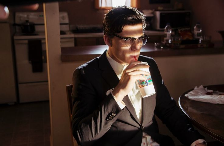 a man sitting at a table drinking from a cup