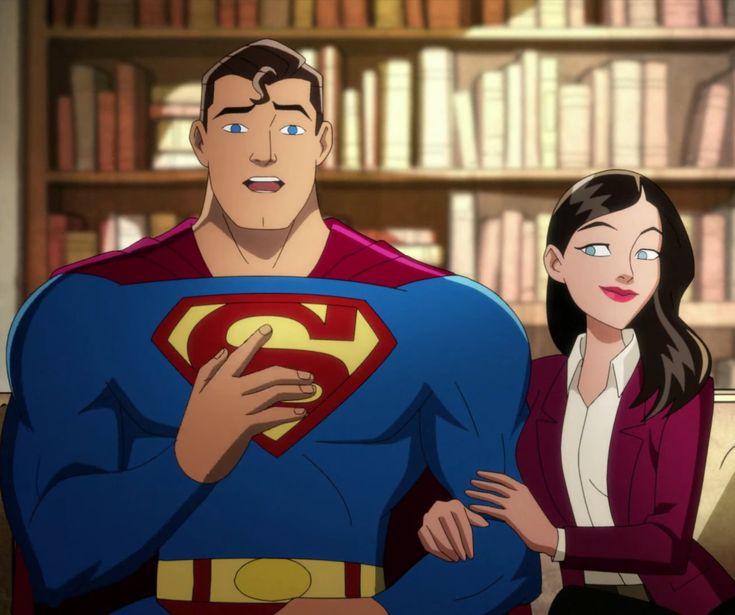 a woman standing next to a man wearing a superman suit in front of bookshelves