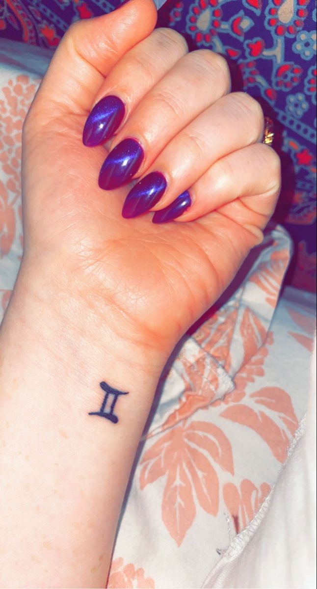 a woman's wrist tattoo with the letter i on it