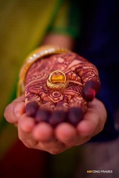 a close up of a person holding a ring on their finger and wearing a henna