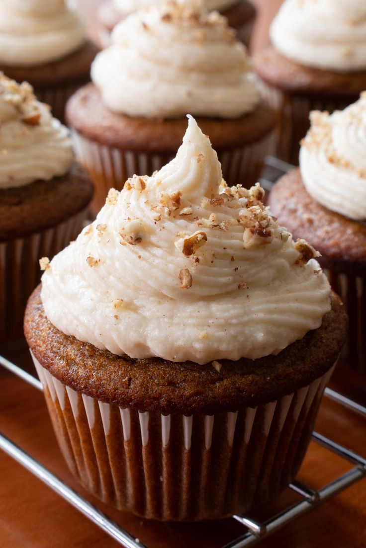 pumpkin cupcakes with brown butter frosting are on a cooling rack and there is text overlay that reads, pumpkin cupcakes with brown butter