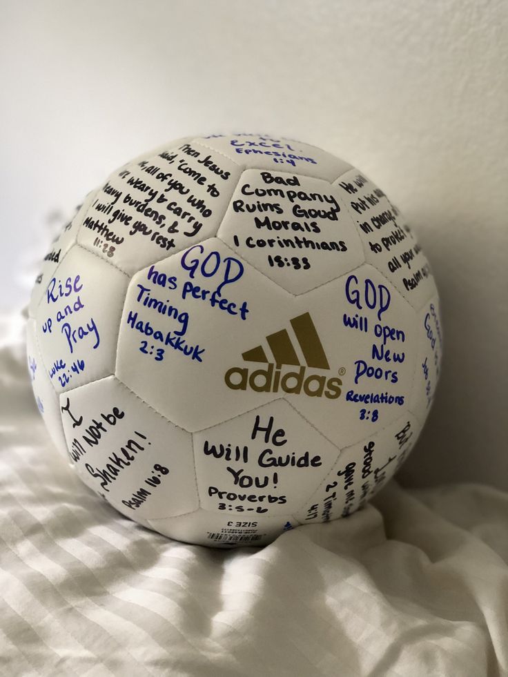 a soccer ball with many different words written all over it on top of a bed