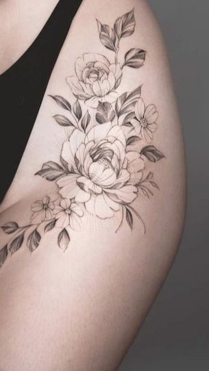 a black and white photo of a woman's thigh with flowers on it,