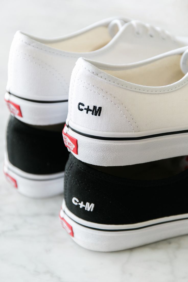 two white and black shoes with the word cm on them sitting on a marble surface