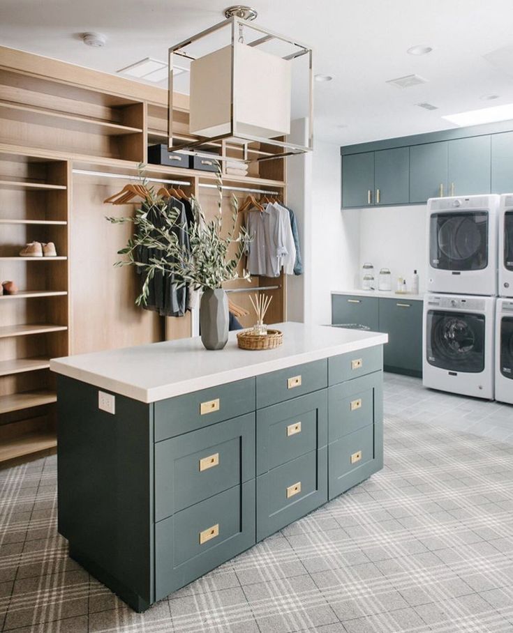 a kitchen with blue cabinets and an island in front of the washer and dryer