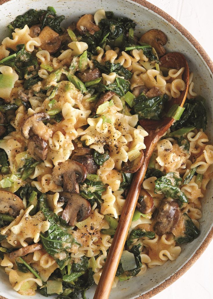 a bowl filled with pasta, mushrooms and spinach