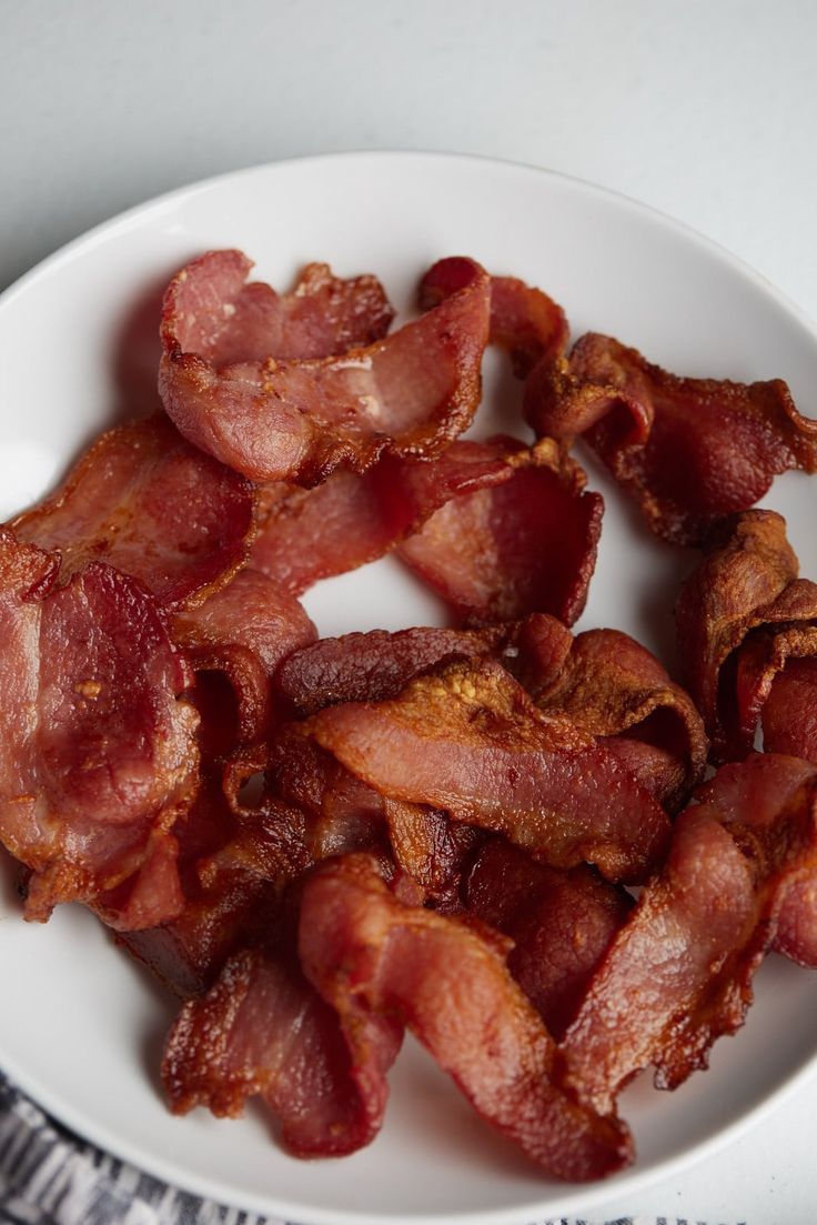 bacon on a white plate sitting on a table