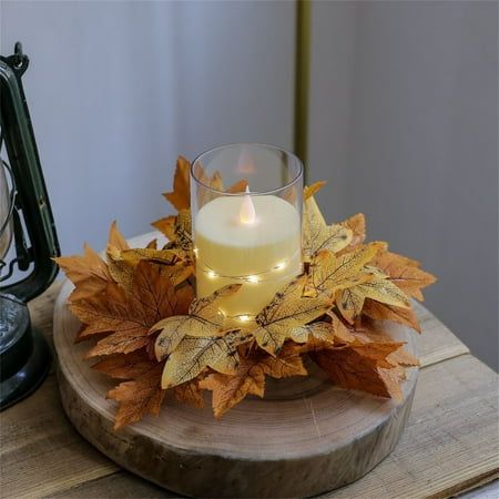 a candle is lit on a wooden tray with leaves