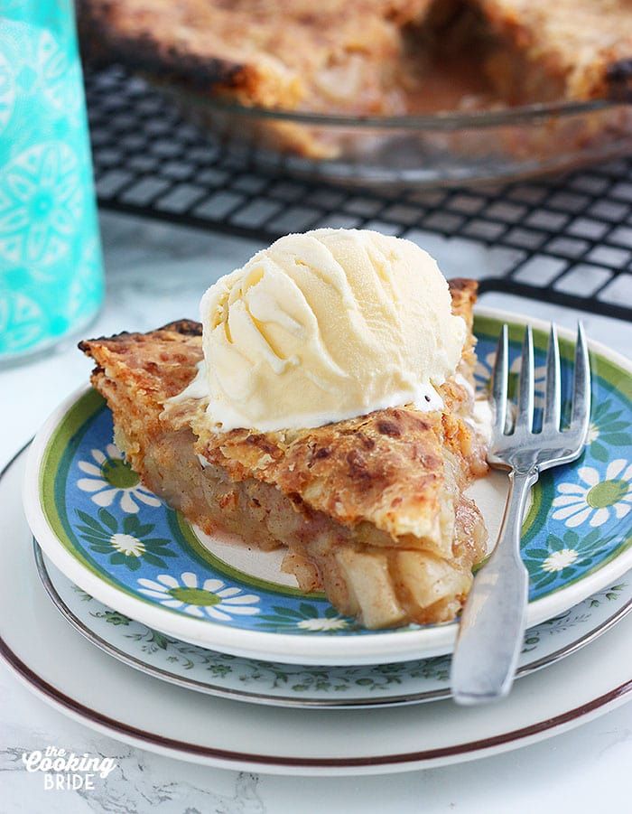 a piece of pie with ice cream on top is sitting on a blue and white plate