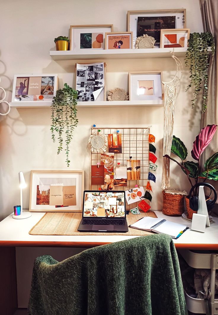 a laptop computer sitting on top of a wooden desk next to a potted plant