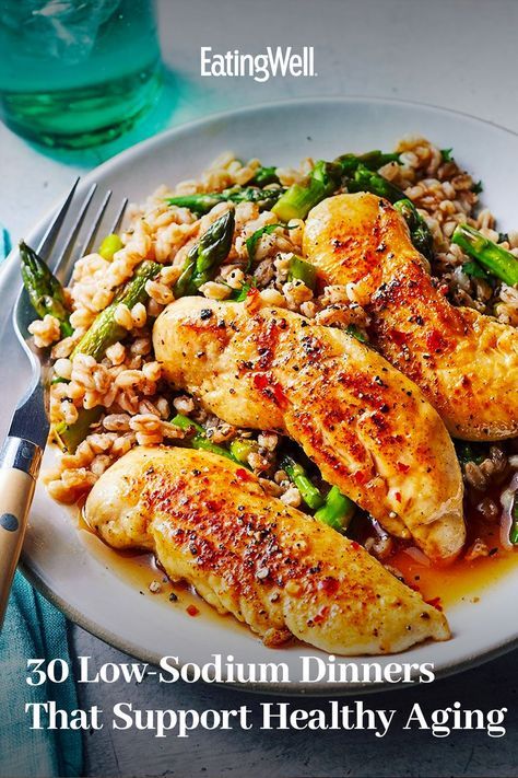 a white plate topped with chicken, rice and asparagus next to a fork