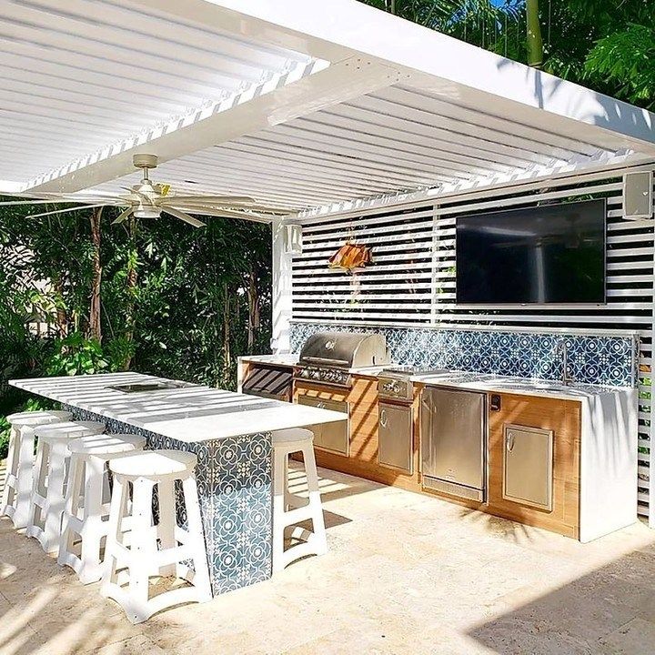 an outdoor kitchen with grill, sink and table