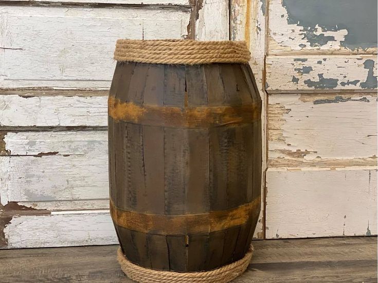 an old wooden barrel with rope hanging from it's side on a wood floor