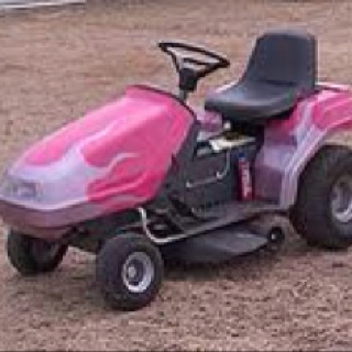 a pink lawn mower sitting on top of a dirt field