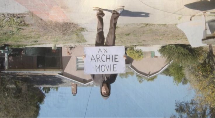 an achie movie sign hanging off the side of a building next to a body of water