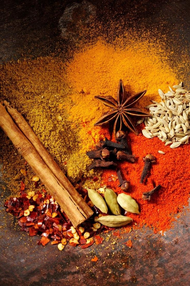 an assortment of spices and spice on a metal surface with cinnamon, star anise, cardamoa seeds, cloves