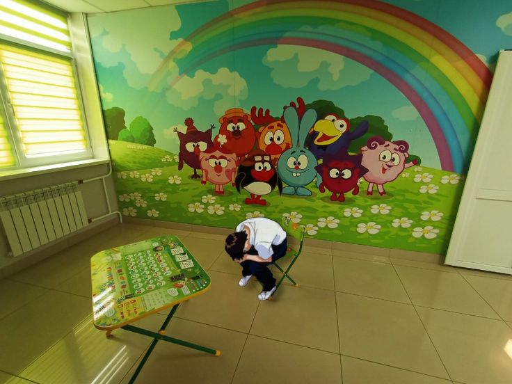 a person sitting on a chair in front of a wall with cartoon characters painted on it