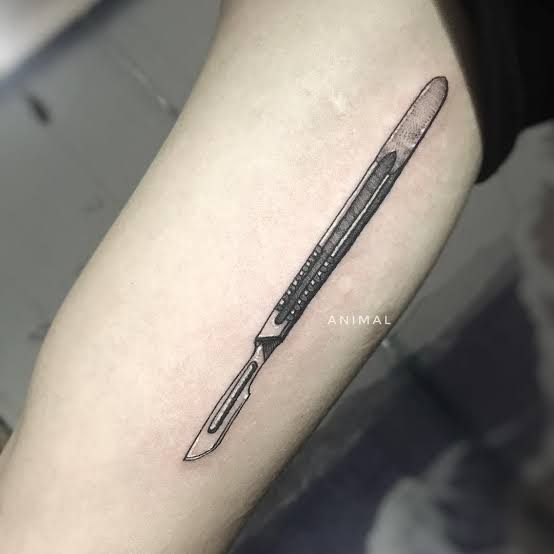 a black and white photo of a pen tattoo on the arm