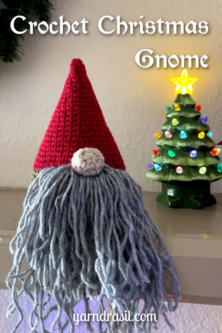 a crochet christmas gnome hat sitting on top of a table next to a tree