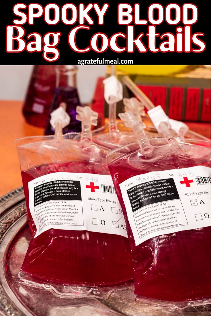 two glasses filled with blood sitting on top of a metal tray next to books and bottles