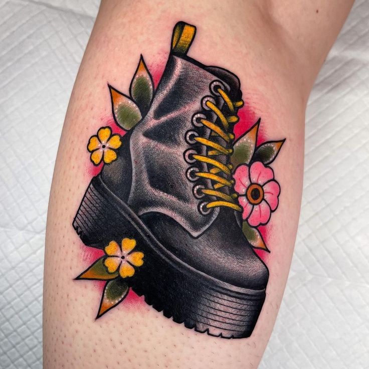 a tattoo with a boot and flowers on the leg, it looks like an old school tattoo