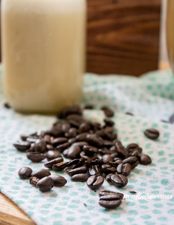 some coffee beans are on a napkin next to a glass of milk