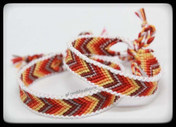 three woven bracelets with red, yellow and white designs on them sitting next to each other