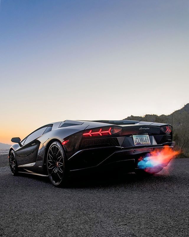 a black sports car parked on the side of a road with flames coming out of it