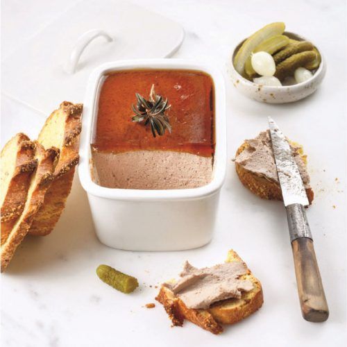 a white bowl filled with food next to bread and pickles