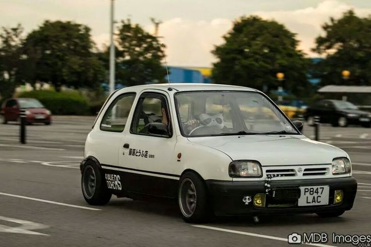 a small white car driving down a street