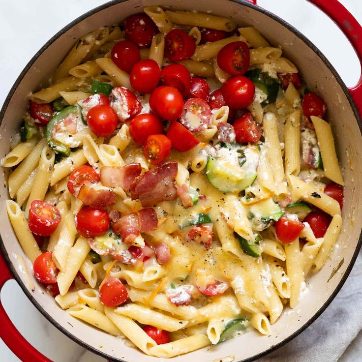 a red pot filled with pasta and tomatoes