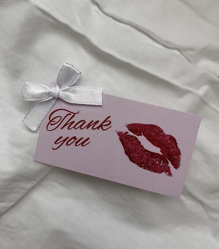 a thank you card with a red lipstick imprint on it and a white ribbon tied around the top